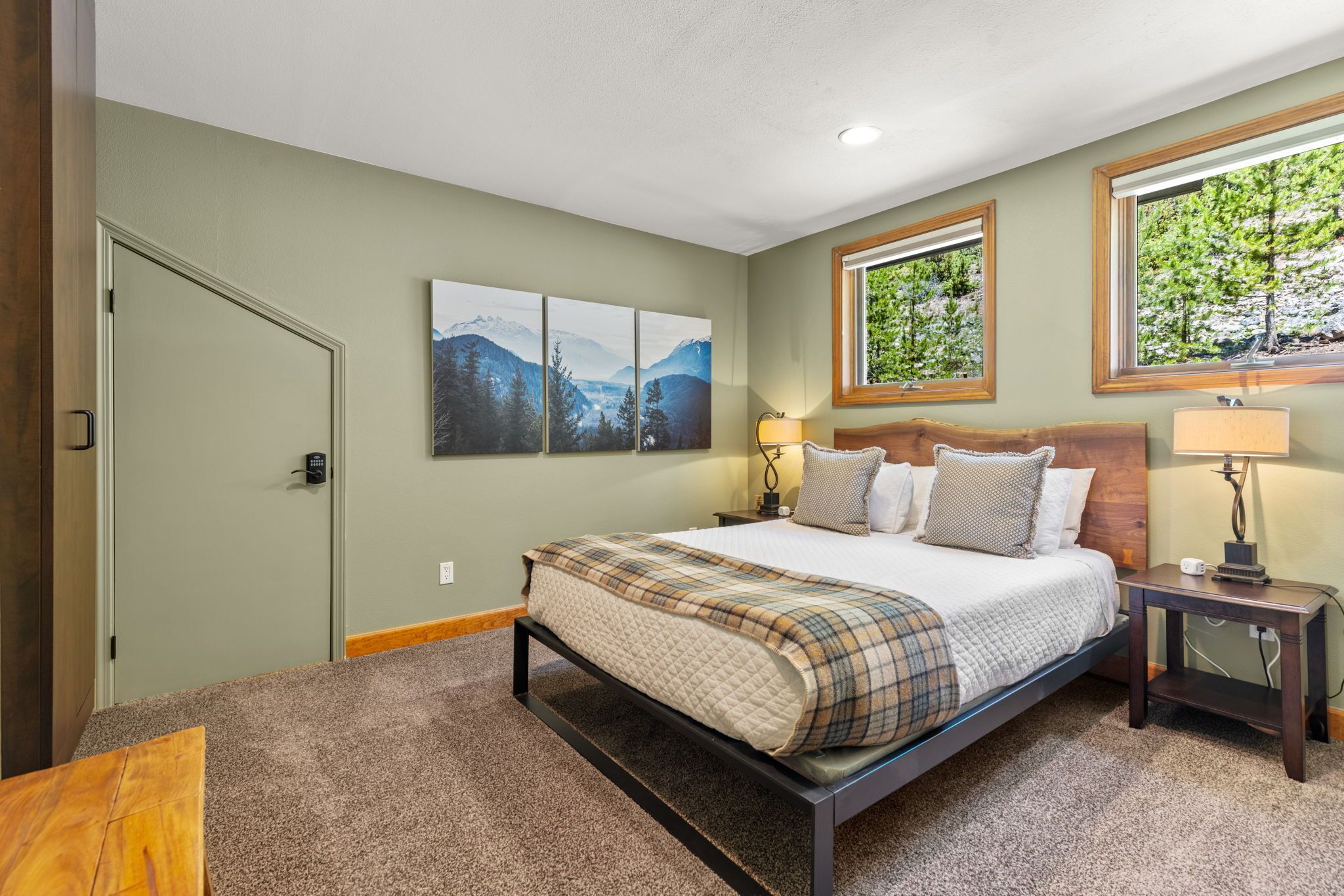 A bedroom with a bed, a nightstand, a window, and a door.