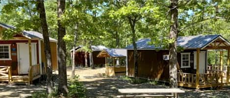A row of wooden cabins with porches, surrounded by trees.