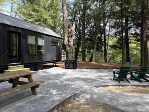 Een rustieke hut met een grindpad, picknicktafel en buitenzitplaatsen.