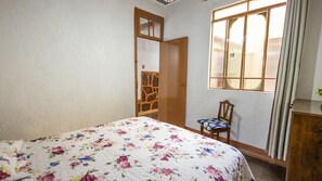 Ein Schlafzimmer mit einem Bett, einem Sessel, einem Kleiderschrank und einem Fenster.
