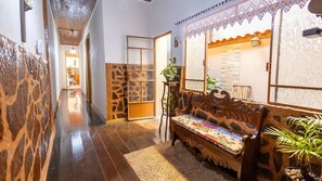A hallway with a wooden bench, a small table with a plant, and a decorative screen.