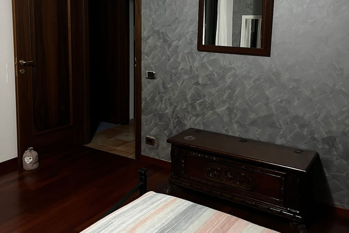 Una habitación con puerta de madera, un espejo, un aparador y una alfombra estampada.