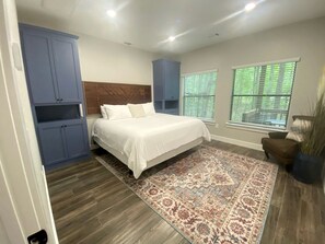 A bedroom with a bed, a patterned rug, a headboard, and a window with blinds. - Cozy Tree House with Beautiful Modern Interior in Livingston, Texas (Livingston)