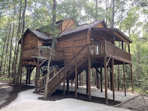 A wooden cabin with a balcony and stairs, surrounded by trees. - Cozy Tree House with Beautiful Modern Interior in Livingston, Texas (Livingston)