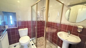 Kylpyhuone, jossa on suihkukaappi, wc, pesuallas ja peili.