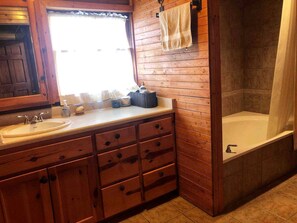 Un baño de madera con lavamanos, espejo y bañera.