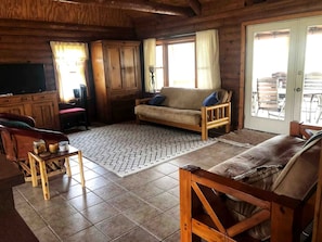 Ein Holzinterieur mit einer Couch, einem Holzstuhl, einem kleinen Tisch und einem Schrank.