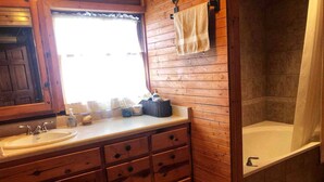 Un baño de madera con lavamanos, espejo y bañera.