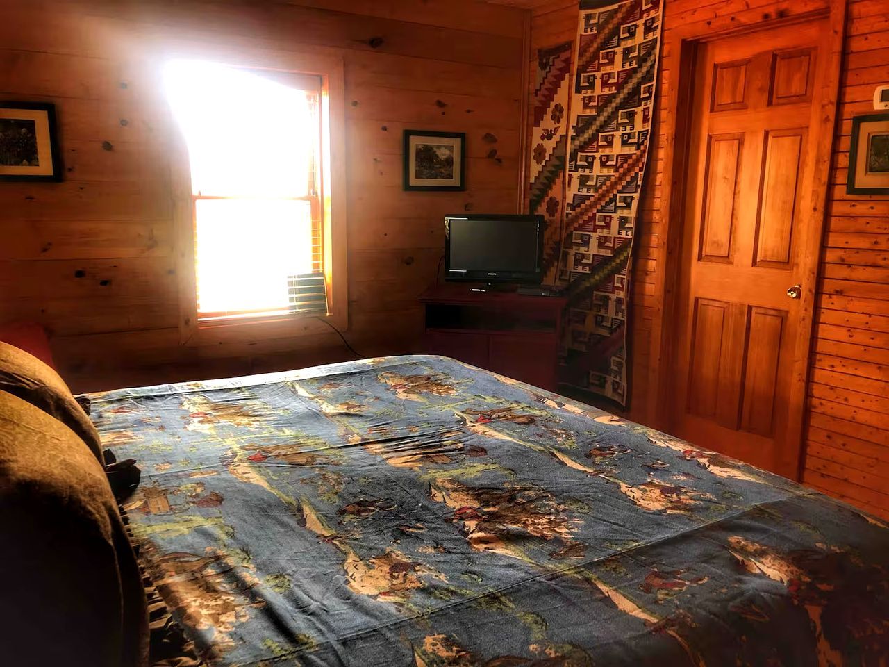 Una habitación con cama, televisión, ventana y puerta.