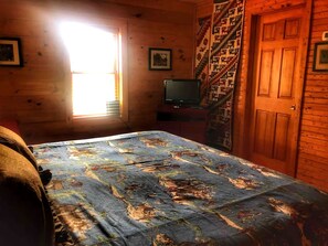A room with a bed, a television, a window, and a door.