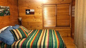 Una habitación de madera con una cama, un adorno con forma de estrella y una puerta con un mensaje.