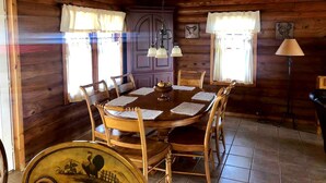 Un comedor de madera con una mesa redonda, sillas y una araña.