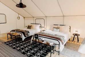Ein Zelttyp-Zimmer mit zwei Betten, einem kleinen Tisch und einer Lampe.