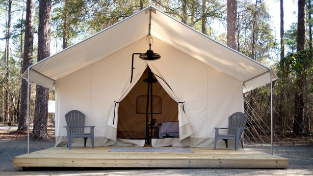 A tent with a central pole, two chairs, and a small platform. - Lake Blackshear Glamping Retreat: Cozy Safari Tent in Cordele, Georgia (Cordele)