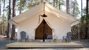 Een tent met een centrale paal, twee stoelen en een klein verhoogd platform.