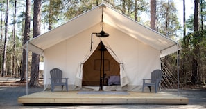 A tent with a central pole, two chairs, and a small platform.