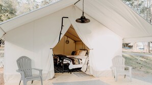 A tent with a bed, two chairs, and a hanging light fixture. - Lake Blackshear Glamping Retreat: Cozy Safari Tent in Cordele, Georgia (Cordele)