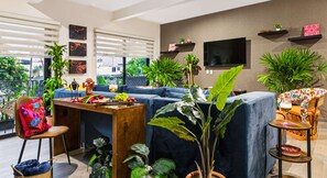 Ein modernes Wohnzimmer mit einem blauen Sofa, einem Holztisch und mehreren Pflanzen.