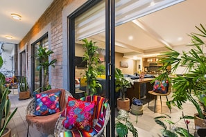 A modern living space with a kitchen, dining area, and seating with potted plants. - Roma Norte 3BR for 11, Big Balcony, Parking & AC (Mexico City)