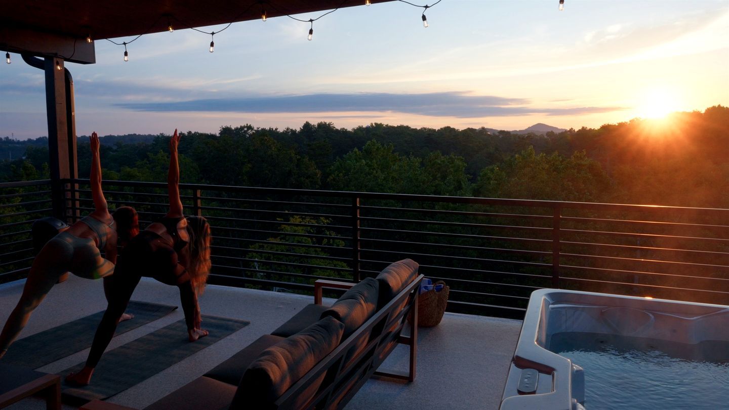 Une terrasse sur le toit avec un jacuzzi, des sièges d’extérieur et une vue panoramique sur les arbres et les montagnes.