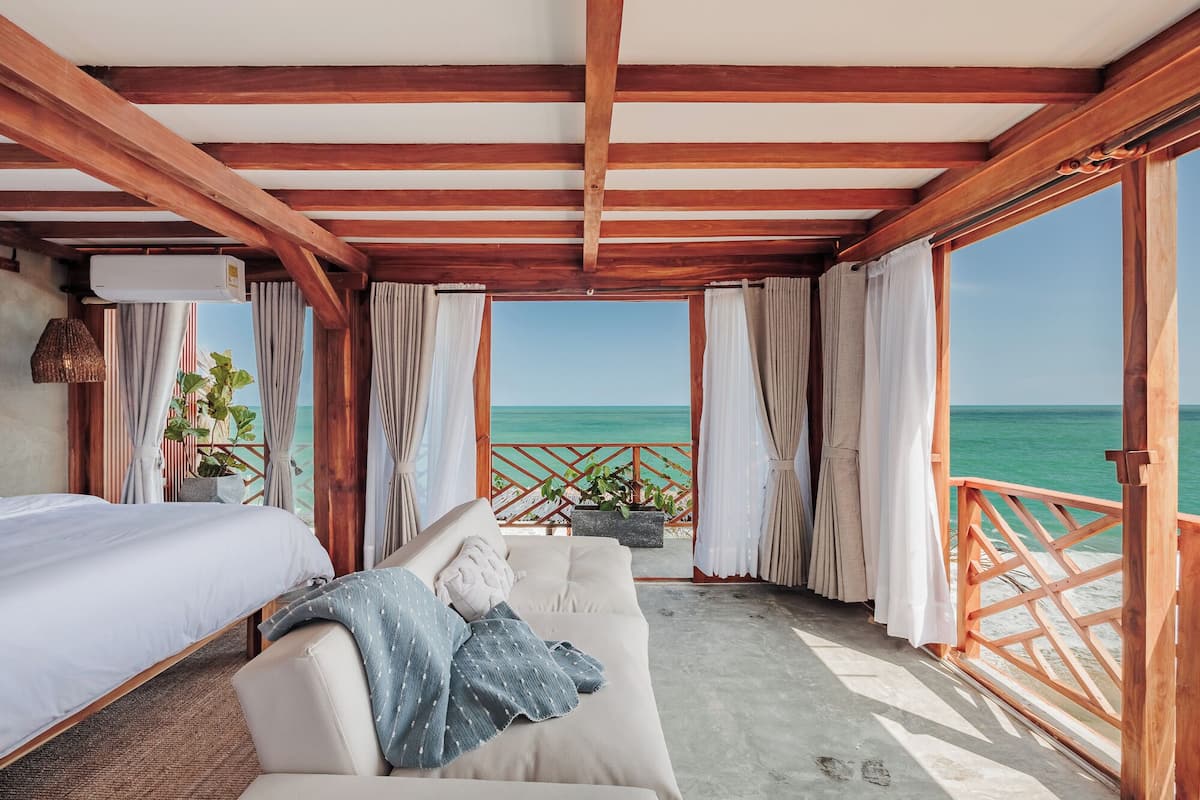 Una habitación con cama, sofá y vista al océano.