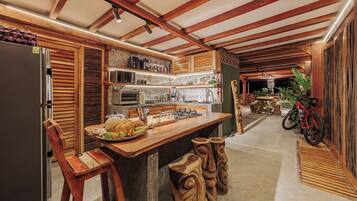 Eine Küche mit Holzbalken, einem Kühlschrank, einer Mikrowelle und einer Holztheke mit Hockern.