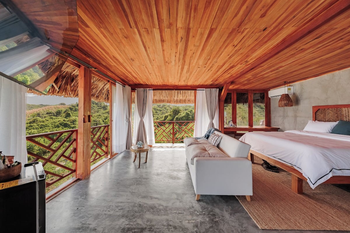 Una habitación con cama, sofá, una mesita y vistas al exterior.