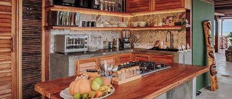 A kitchen with a central island, wooden beams, and a green wall.