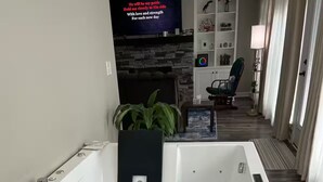 Moderni kylpyhuone, jossa on suuri kylpyamme, ohjauspaneeli ja televisio, jossa näkyy viesti.