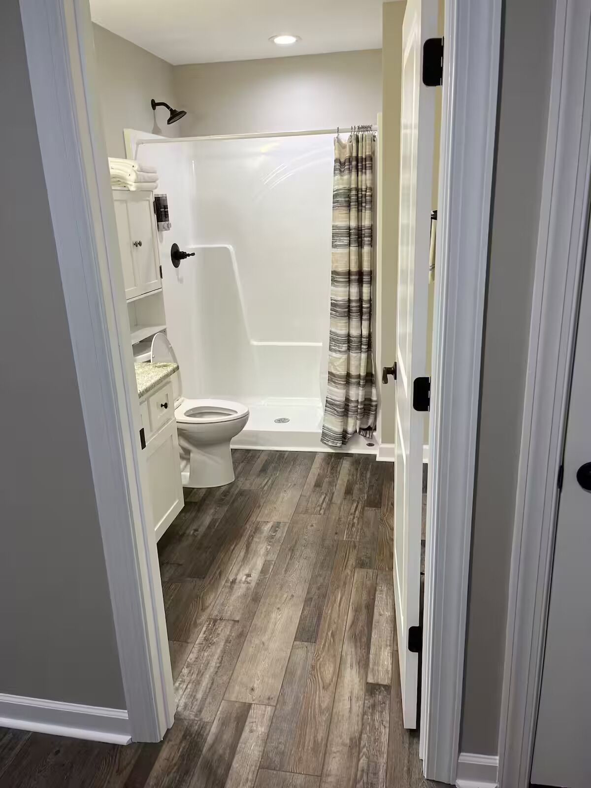 Une salle de bain avec des toilettes, une douche et un plancher en bois.