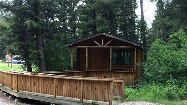 Een houten chalet met terras, omringd door bomen.