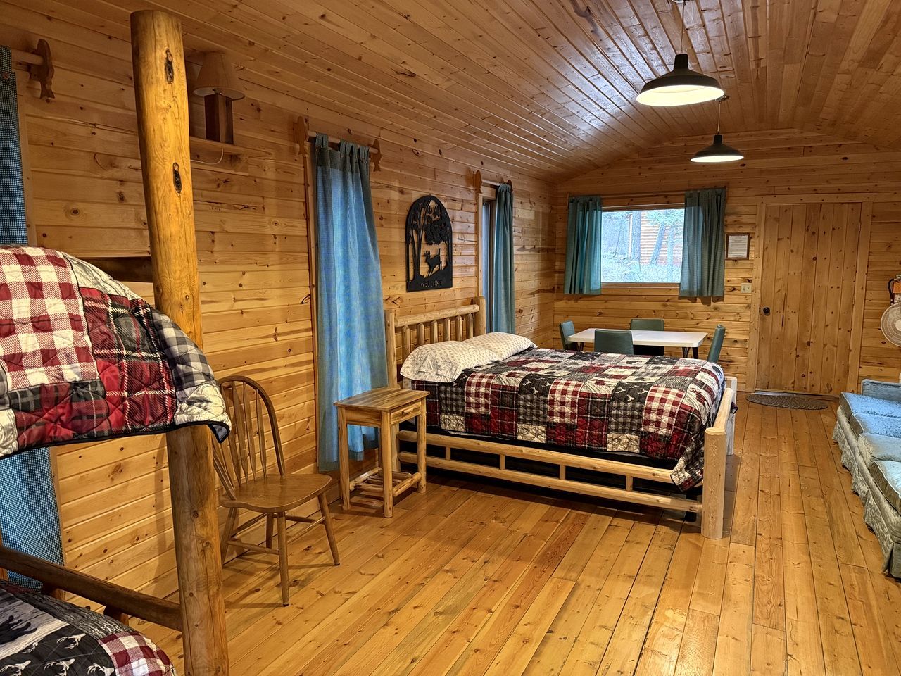 A cabin interior with a bed, a table, and a chair.