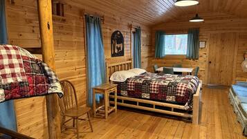 A cabin interior with a bed, a table, and a chair.