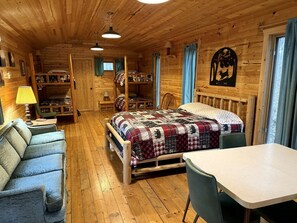 Ein Ferienhäuschen im Inneren zeigt ein Etagenbett, einen Esstisch und eine Sitzecke.