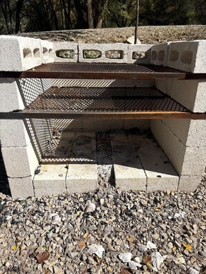 Una estructura de concreto con una reja metálica, rodeada de grava y árboles.