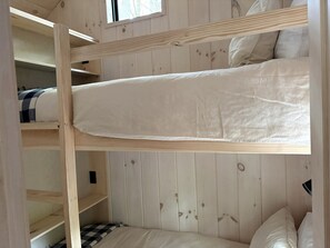 Een slaapkamer met stapelbed, houten wanden en een raam.