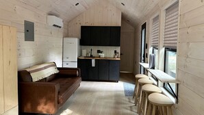 A compact kitchen with a central island, a sofa, and a bar area with stools.