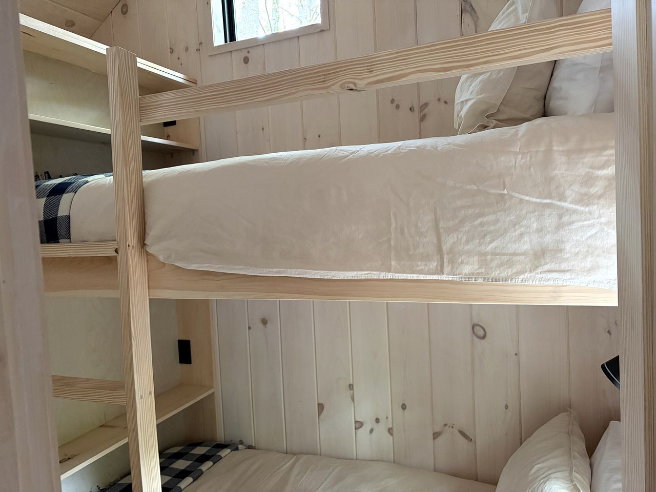 A bunk bed room with wooden walls and a window.