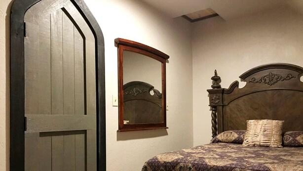 Une chambre à coucher avec un lit, une porte en bois et un miroir au mur.