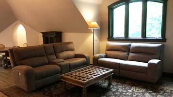Sala em estilo loft com dois sofás, uma mesa de centro, um abajur e uma janela grande.