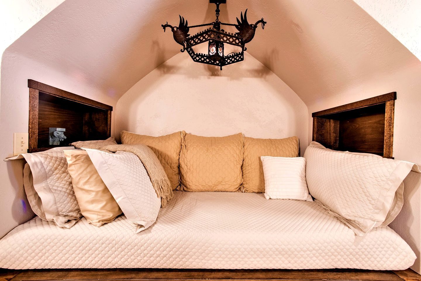 Ein gemütlicher, gewölbter Raum mit einem Bett, einer Chandelüster und Holzkopfteilen.