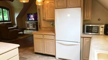 A kitchen with a white refrigerator, microwave, and wooden cabinets.