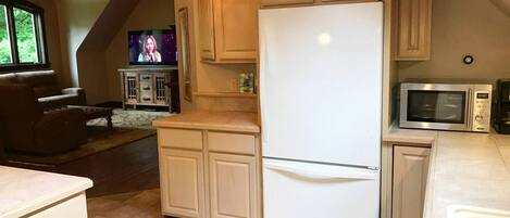 A kitchen with a white refrigerator, microwave, and wooden cabinets.
