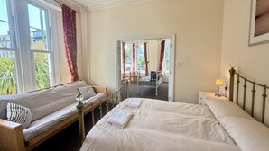 Een hotelkamer met twee bedden, een zithoek en uitzicht op de straat.
