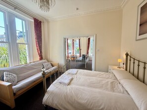 Ein Hotelzimmer mit zwei Betten, einer Sitzecke und Blick auf die Straße.