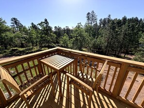 Eine Holzterrasse mit Tisch und Stühlen, umgeben von einem Wald.