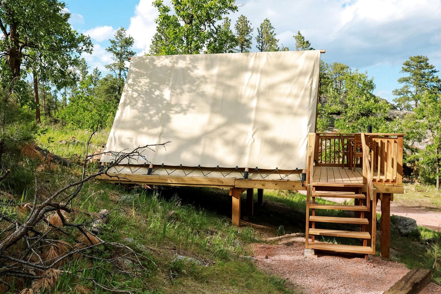 A wooden deck with a canopy, surrounded by trees and natural terrain.