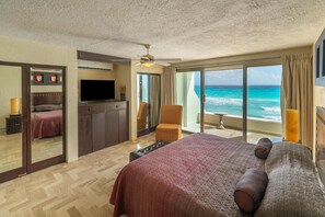 A hotel room with a bed, a TV, a chair, a balcony with ocean view, and a ceiling fan. - Luxury Ocean View Villa - Hotel Zone Solymar Condo Villa 11 (Cancún)