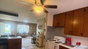 A kitchen with a ceiling fan, a stove, and a sink.