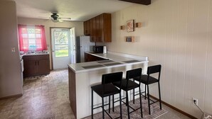 A kitchen with a central island, bar stools, and a ceiling fan.